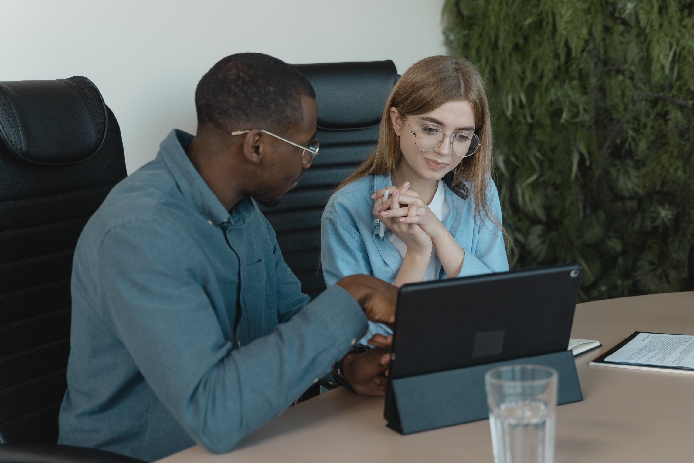 Two people looking at a table while one points to the screen.