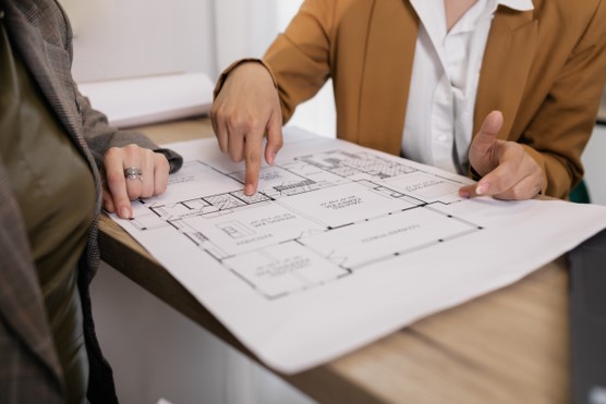 Two people pointing at a document on a table.