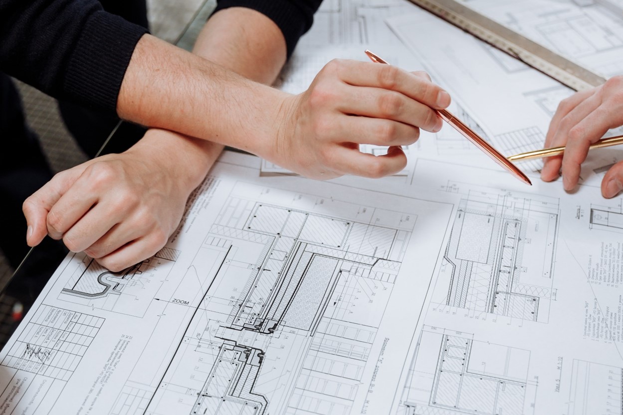 Two people's hands holding pens going over a design document.