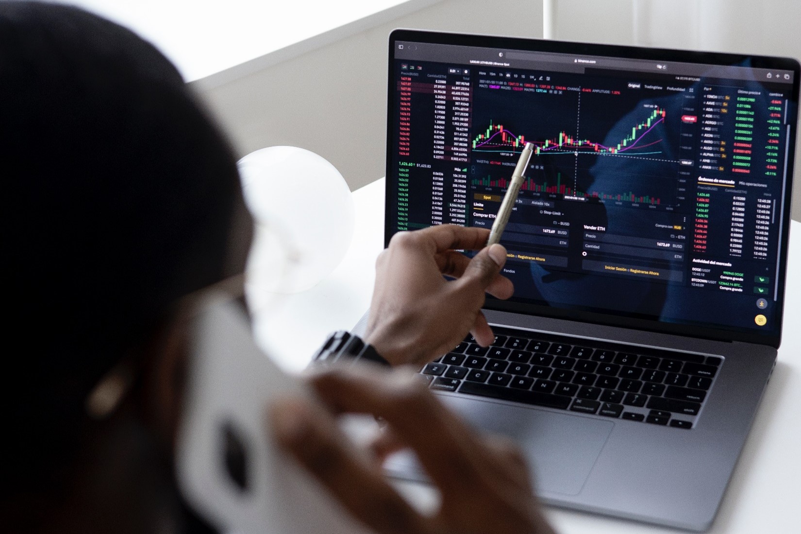 A man pointing to a graph on his laptop screen.