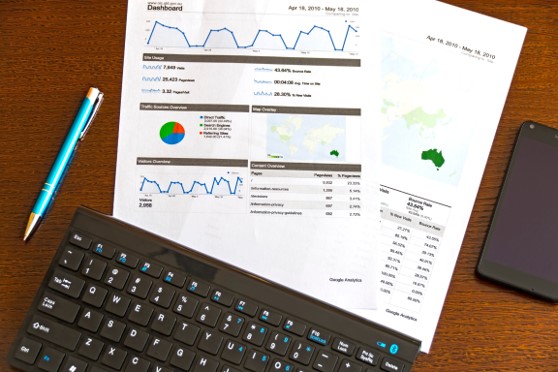 Two documents showing various charts and graphs along side a keyboard on a desk.