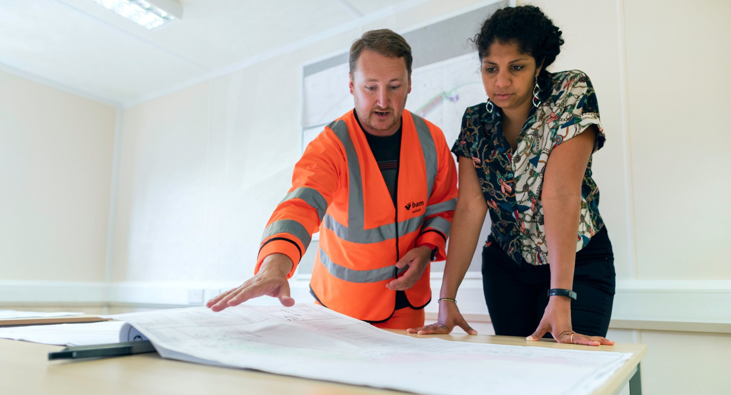 Two people looking at blueprints for a building.