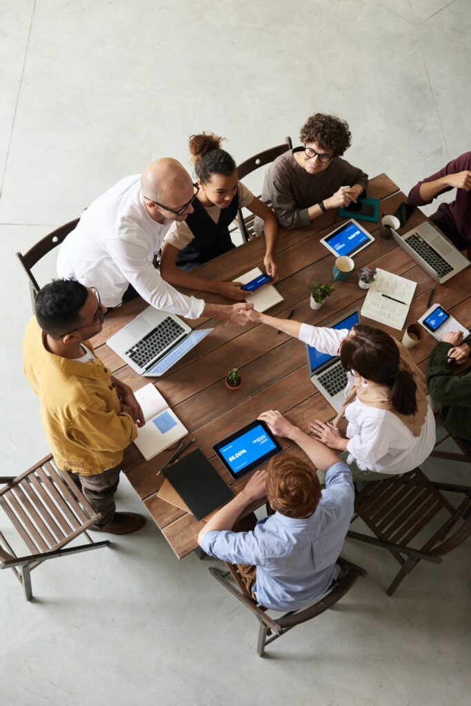 A team of people sitting around a table while doing work on their laptops and tablets.